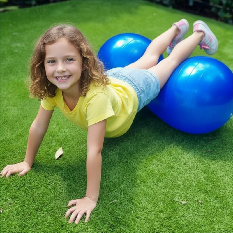 Child playing with blue exercise balls on a grassy area
