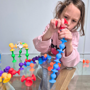 Child playing with colourful suction pieces from an educational toy game on a glass table